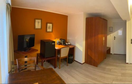 a living room with a desk with a television and a table at Hotel Restaurant Hestia in Eijsden
