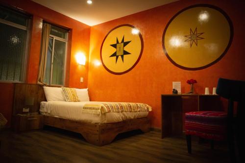 a bedroom with orange walls with a bed and two large mirrors at Chakana Hotel Boutique Centro in Quito