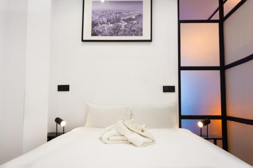 ein Schlafzimmer mit einem weißen Bett und Handtüchern darauf in der Unterkunft 31 Apartments - Luxe in het centrum van Malaga in Málaga