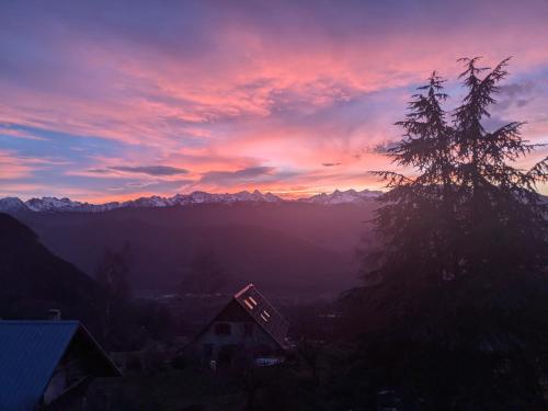 un coucher de soleil dans les montagnes avec une maison et un arbre dans l'établissement Appartement de plain-pied en montagne avec vue merveilleuse sur le massif de Belledonne, à Saint Bernard du Touvet