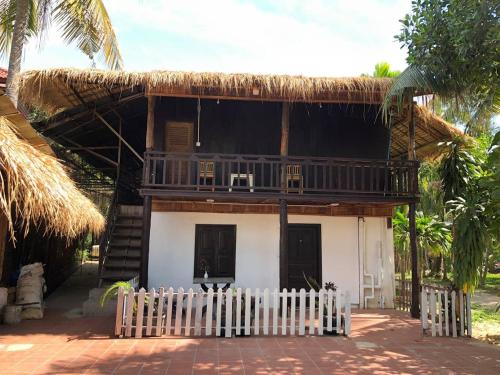 uma pequena casa com um telhado de palha e um alpendre em Yi family Homestay em Siem Reap
