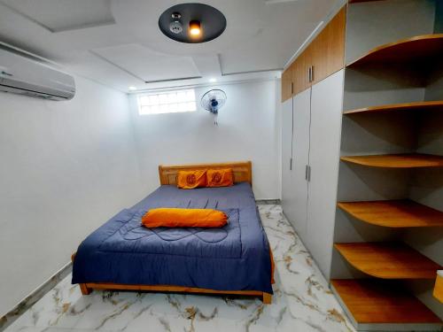 um quarto com uma cama com lençóis azuis e almofadas laranja em MM's House em Ho Chi Minh