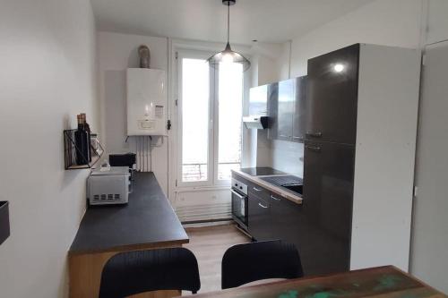 uma cozinha com um frigorífico preto e uma mesa em Appartement cosy 2 chambres em Nancy
