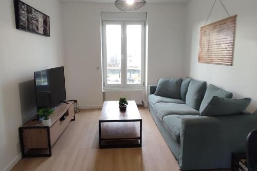 uma sala de estar com um sofá azul e uma mesa de centro em Appartement cosy 2 chambres em Nancy