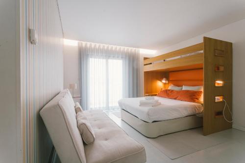 a bedroom with a bed and a couch at Bica, luxury heated penthouses with jacuzzi and large terrace in Baleal in Baleal