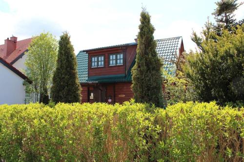 una casa con un tetto verde dietro una siepe di Sielski domek Grzybowo a Grzybowo