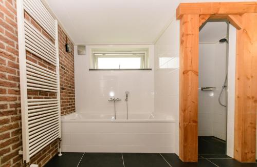 een badkamer met een bad en een bakstenen muur bij Atelier / Guesthouse Arriën - De Studio van Slim in Arriën