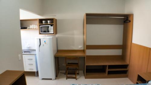 a small kitchen with a refrigerator and a table at Inspire GuestHouse in Campos do Jordão