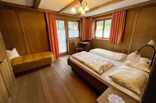 a bedroom with two beds and a table and windows at Ansitz Steiner in Dobbiaco