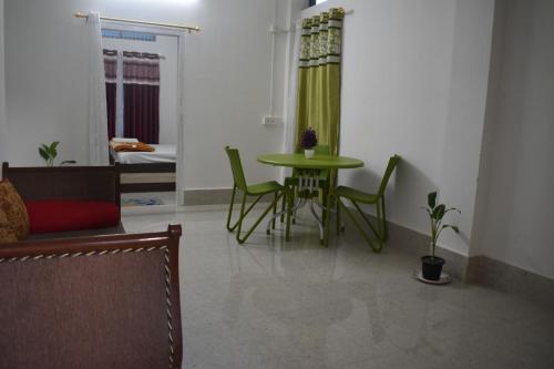 a living room with a green table and chairs at Purabi's Nest in Tezpur