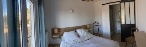 1 dormitorio con 1 cama con sábanas blancas y ventana en La Rolande, en Aix-en-Provence