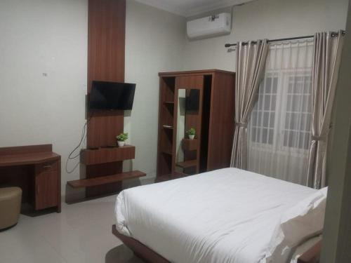 a bedroom with a bed and a dresser and a television at Griya Sambilegi in Yogyakarta