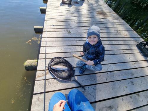 a young boy sitting on a dock with a tennis racket at Cozy rustical house in the highland (entire place) in Kožlí