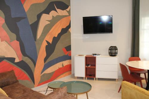 a living room with a couch and a tv on a wall at Le gite des 3 mousquetaires in Amboise