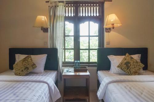 two beds in a room with a window at Ubud Kerta City Hotel in Ubud