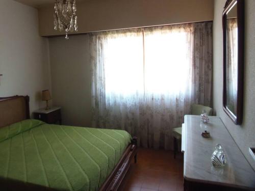 Un dormitorio con una cama verde y una ventana en Dpto en Miramar, 2 amb, ubicación ideal, cochera. en Miramar