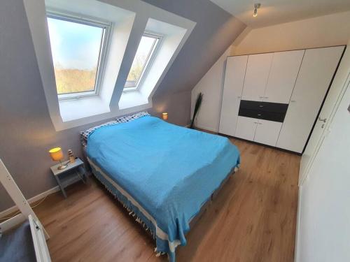 a bedroom with a blue bed and two windows at Kiel-Russee Familienwohnung, Lademöglichkeit, Co2 Frei in Kiel