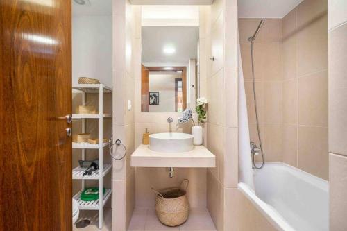 a bathroom with a sink and a tub and a mirror at Salgados Beach House 2-Bedroom & 7 Pools in Guia