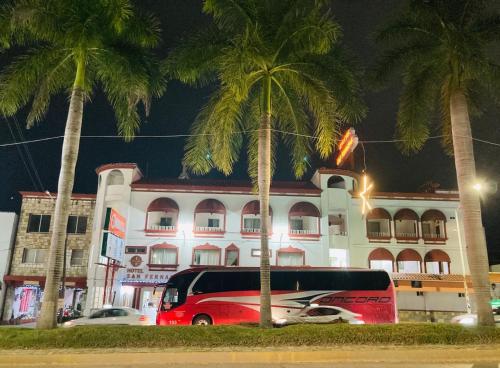 une camionnette rouge garée devant un immeuble planté de palmiers dans l'établissement Hotel San Fernando Ciudad Valles, à Ciudad Valles