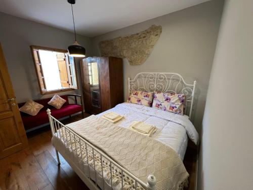 a bedroom with a white bed and a red chair at Eftis - Renovated Traditional House in Omodos