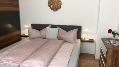 1 dormitorio con 1 cama con sábanas y almohadas rosas en beim Holzwurm Andy, en Sankt Leonhard im Pitztal