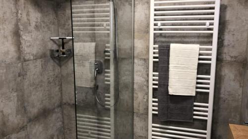 cabina de ducha con puerta de cristal y toallas en beim Holzwurm Andy, en Sankt Leonhard im Pitztal
