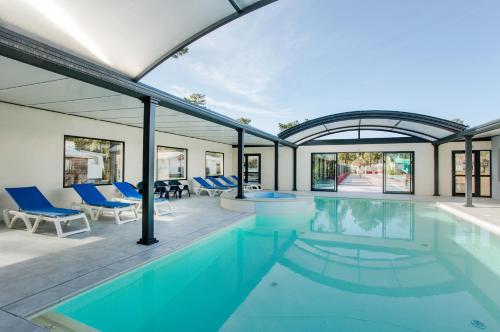 a swimming pool in a house with blue chairs at Camping Le California in Saint-Jean-de-Monts
