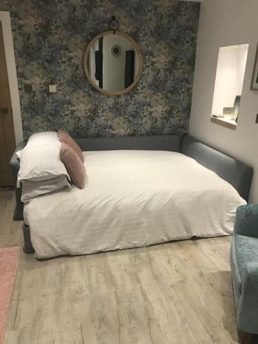 a bedroom with a white bed and a mirror at Riverside Hideaway in Kincraig