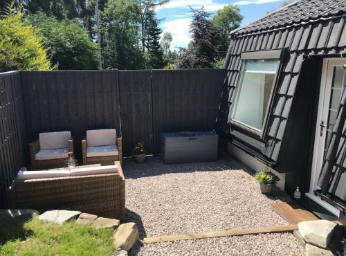a backyard with two chairs and a fence at Riverside Hideaway in Kincraig