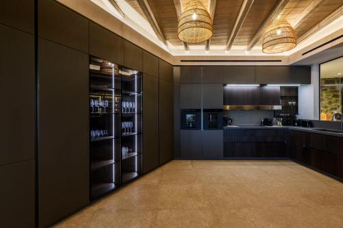 eine große Küche mit schwarzen Schränken und einer Bar in der Unterkunft Muse Mansion Mykonos in Ornos