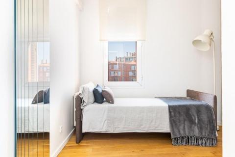 biała sypialnia z łóżkiem i oknem w obiekcie Idyllic apartment in BCN beach w Barcelonie