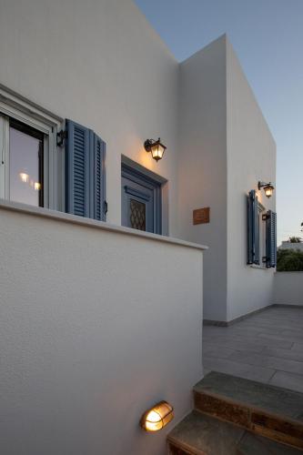 a room with a white wall with a bench and windows at Ruby's summer house with spacious garden and free parking in Gavrion
