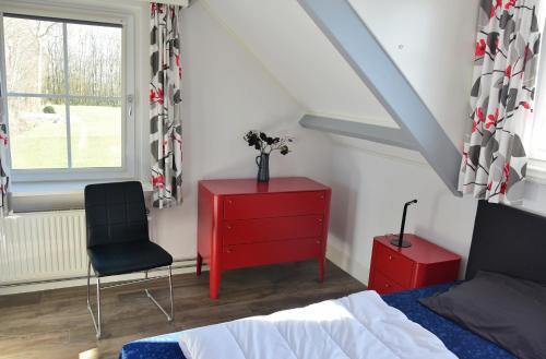 a bedroom with a red dresser and a red chair at Woning zeldenrust 6 in Oostkapelle