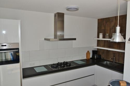 een witte keuken met een fornuis en een wastafel bij Woning zeldenrust 6 in Oostkapelle