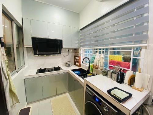 eine kleine Küche mit weißen Schränken und einem Waschbecken in der Unterkunft Haira Muslim Homestay in Pasir Gudang