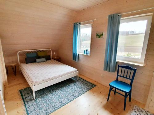 a bedroom with a bed and a chair and a window at Blue Lake House in Lekarty