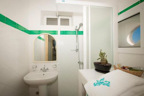 uma casa de banho branca com um lavatório e um chuveiro em Stromboli Trekking Accommodation - Room and Excursion for 2 included em Stromboli