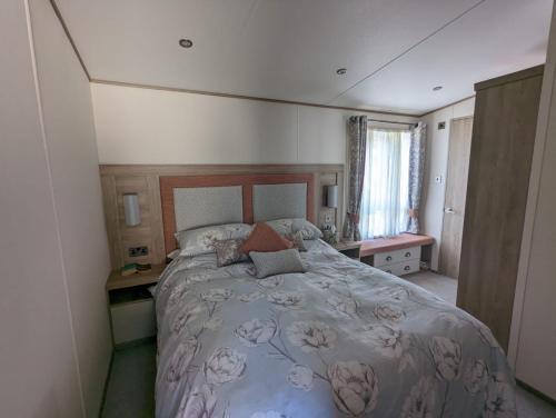 a bedroom with a large bed and a window at STUNNING LUXURY Caravan on edge of New Forest on SHOREFIELD Country Park ENTERTAINMENT AND LEISURE PASSES INCLUDED in Milford on Sea