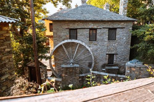 a stone building with a wheel in a yard at Palio Eleotrivio Guesthouse in Agios Lavrentios