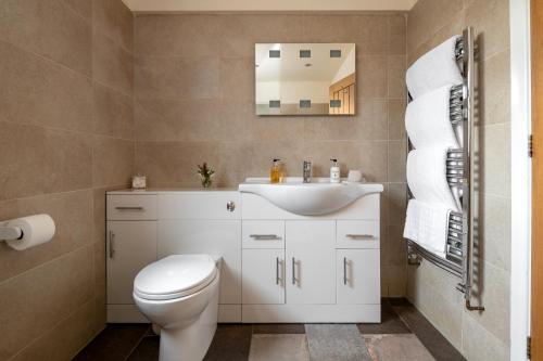 a bathroom with a white toilet and a sink at The Country Lodge at Hill House Farm Cheshire in Tarporley