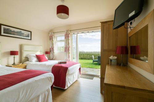 a hotel room with two beds and a flat screen tv at The Country Lodge at Hill House Farm Cheshire in Tarporley