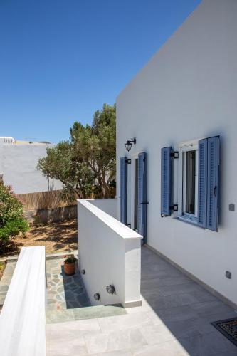 a white building with blue shuttered windows and the ocean at Ruby's summer house with spacious garden and free parking in Gavrion