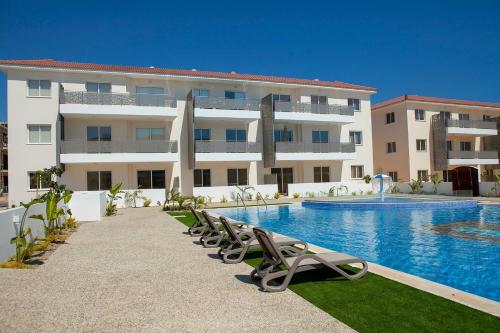 a hotel with a swimming pool and chairs in front of a building at Carme at the Beach - Mythical Sands in Paralimni
