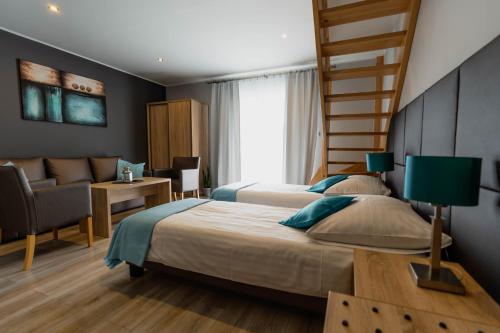 a bedroom with two beds and a chair and a staircase at Tramontana Family & Wellness in Darłówko
