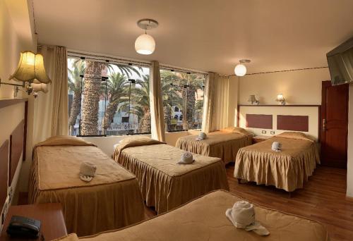 Habitación con 3 camas y ventana grande. en HOTEL AVENIDA, en Tacna