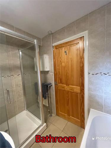 a bathroom with a shower and a wooden door at Super deluxe extra large 3 bedroom apartment in Stanley