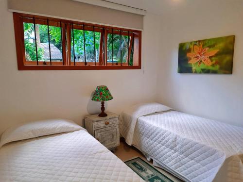 2 camas individuales en un dormitorio con ventana en Casa dos beija Flores, 80 mts da praia do centro, en Bombinhas