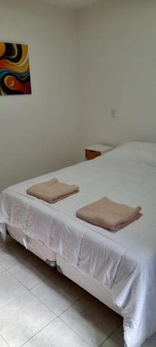 Una cama blanca con dos almohadas encima. en Departamento Maipu centro en Maipú