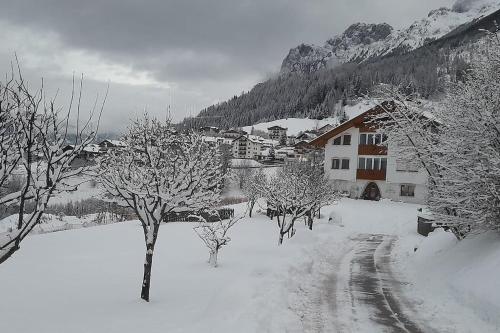 a snow covered village with a house and trees at Ciasa Gran Panorama Moena in Moena