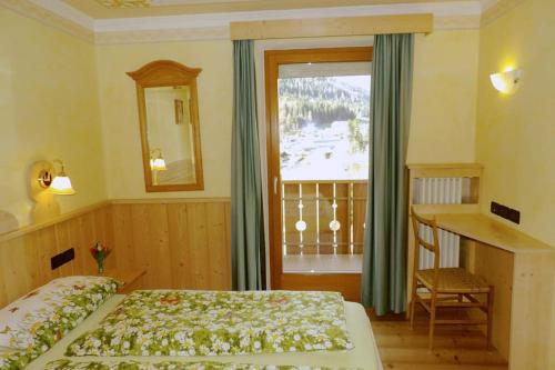 - une chambre avec un lit, un bureau et une fenêtre dans l'établissement Ciasa Gran Panorama Moena, à Moena